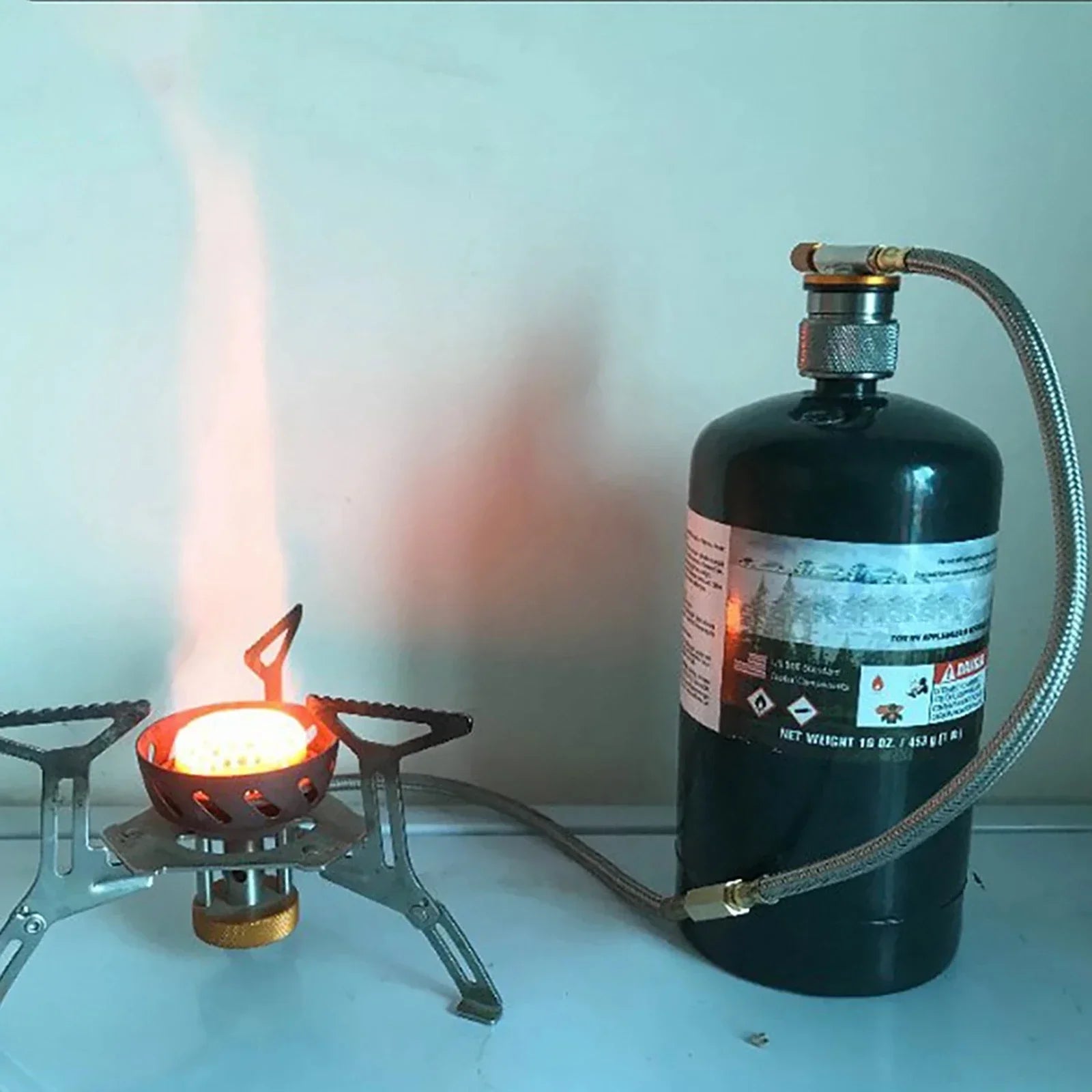 Gas canister connected to a small stove using the butane/propane tank valve conversion head offered by the Northeast's premier outdoor gear provider, The Adirondack Tool Co.