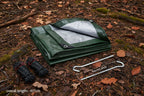 Green tarp with silver lining, ropes, and stakes on a white background, offered by the best hiking and camping gear provider in the Northeast, The Adirondack Tool Co.