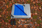 Folded tarp with blue and gray sections, ropes, and hooks on a white background - offered by the best hiking and camping gear provider in the Northeast, The Adirondack Tool Co.
