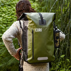 Person wearing a green backpack with 'COR Surf' branding in a natural setting
