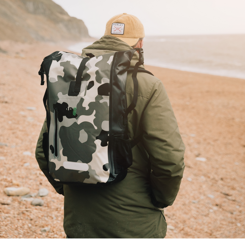 Person wearing a camouflage backpack on a beach
