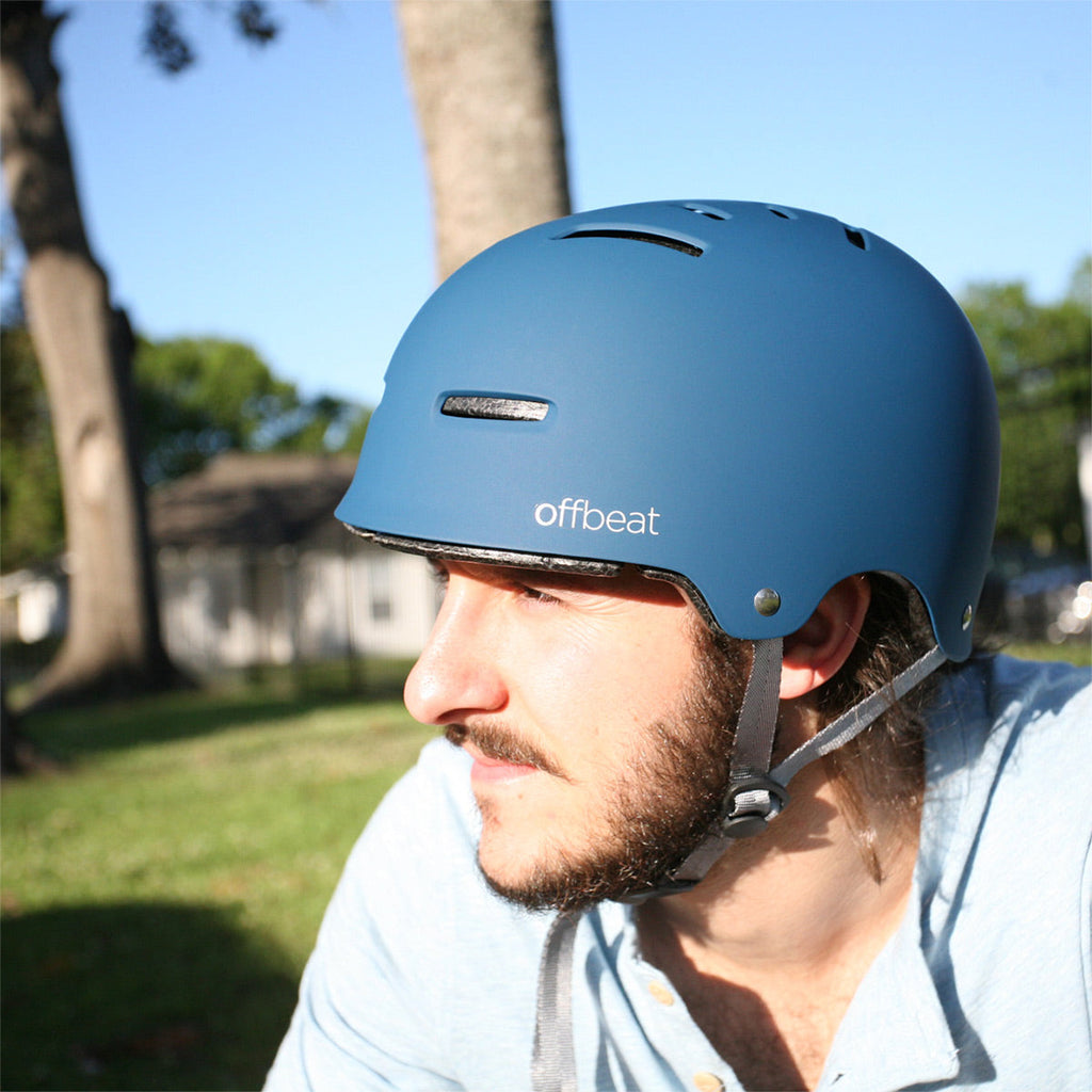 Man wearing a blue helmet with 'offbeat' branding outdoors - offered by the best outdoor gear store in New York, The Adirondack Tool Co.