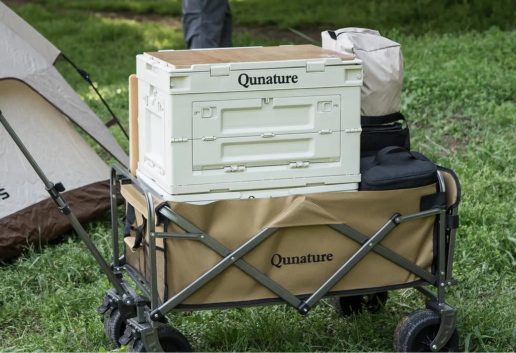 Camping cart with storage crate in a grassy area, featuring Qunature branding - offered by the best outdoor gear store in Virginia, The Adirondack Tool Co.