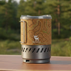 Portable stove with topographic design and brand logo on a forest background - offered by the best camping gear store in Pennsylvania, The Adirondack Tool Co.