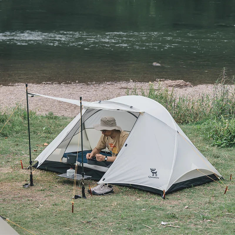 Person camping by a river with a Qunature 2-person tent - offered by the best camping gear store in Massachusetts, The Adirondack Tool Co.