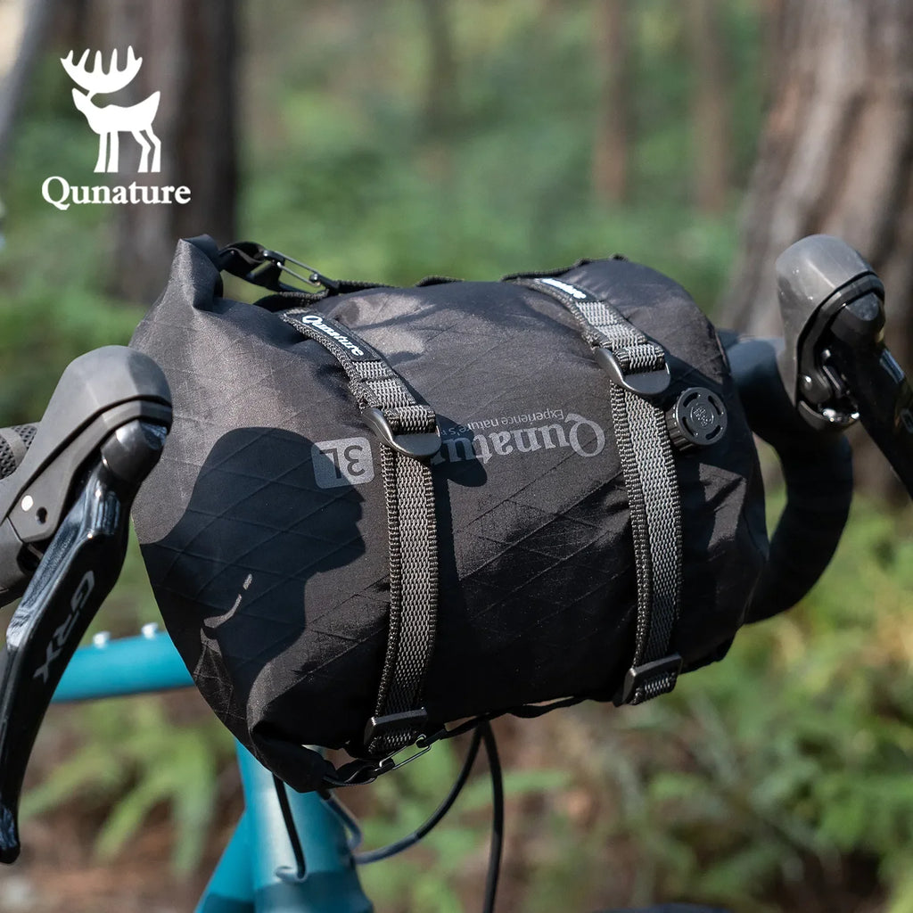 Black bike bag with Qunature branding attached to a bicycle handlebar in a forest setting - offered by the best biking gear store in New York, The Adirondack Tool Co.