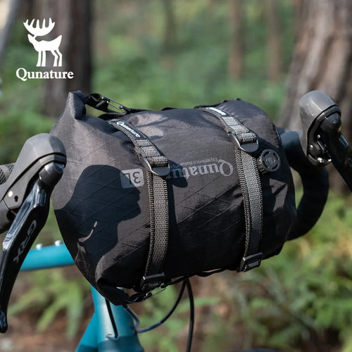 Black bike bag with Qunature branding attached to a bicycle handlebar in a forest setting - offered by the best biking gear store in New York, The Adirondack Tool Co.