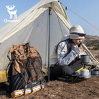 Person camping with a tent, backpack, and cooking gear in a natural setting.